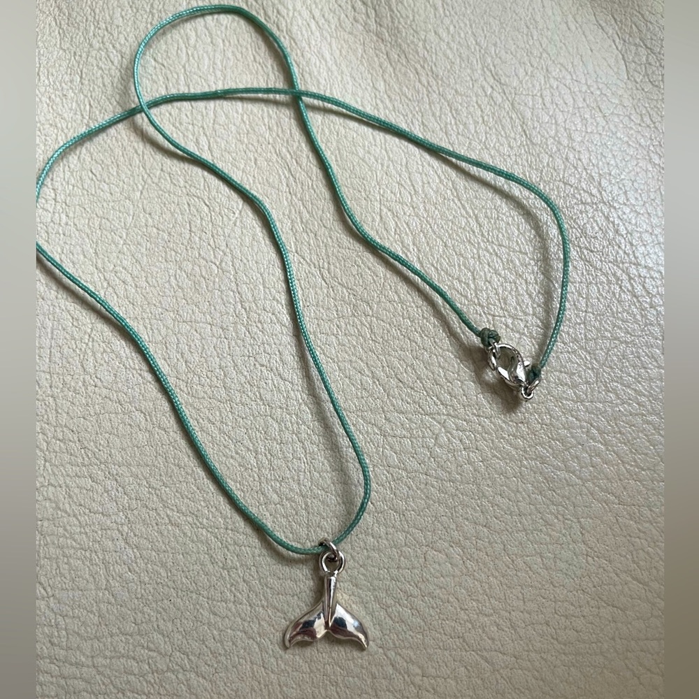 Beautiful silver dolphins tale on a blue necklaces